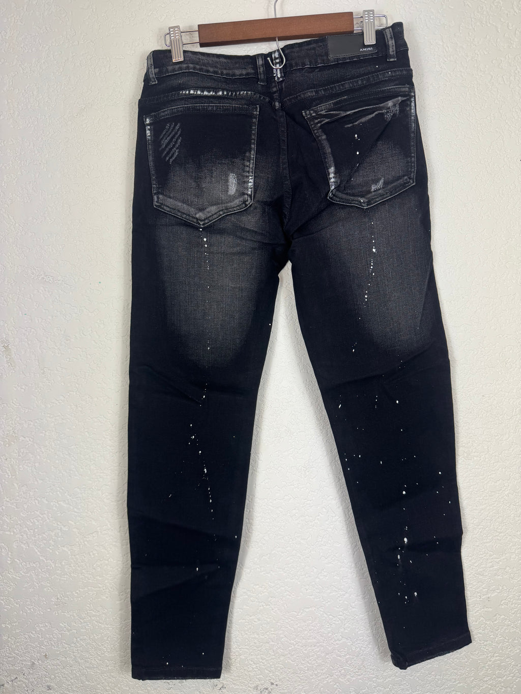 Amiri brand jeans featuring distinctive white starburst embroidery and a prominent logo patc