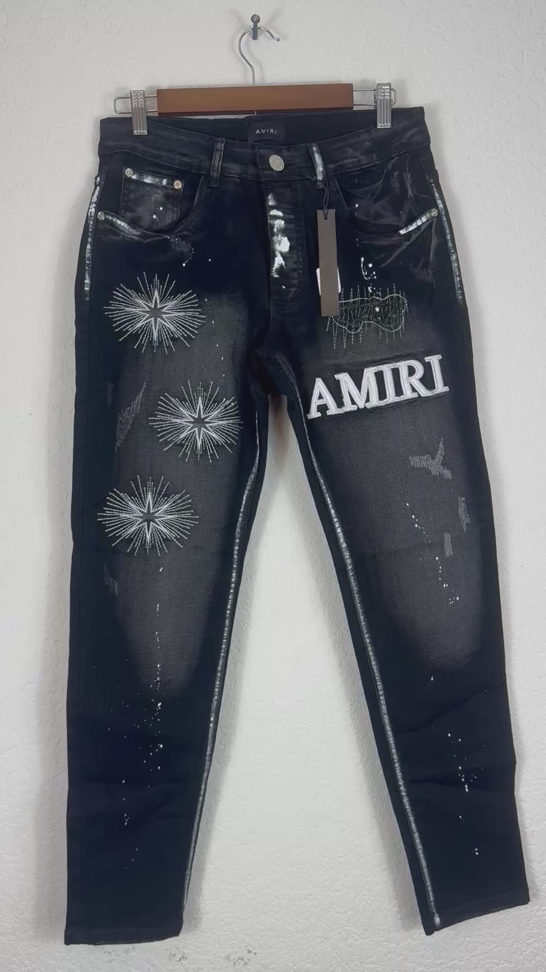 Amiri brand jeans featuring distinctive white starburst embroidery and a prominent logo patc